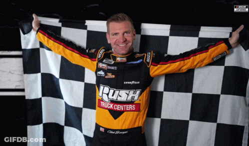 A Man Holding A Checkered Flag That Says Rush Truck Centers On It GIF