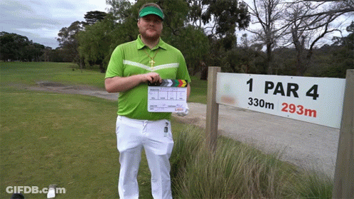 A Man Holding A Clapper Board Stands In Front Of A Sign For 1 Par 4 GIF