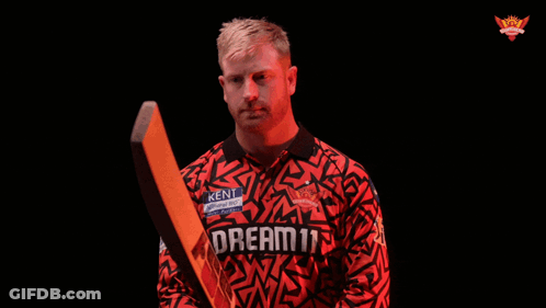 A Man Holding A Cricket Bat With The Word Realm On His Jersey GIF