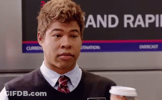 A Man Holding A Cup Of Coffee In Front Of A Sign That Says Rapid GIF