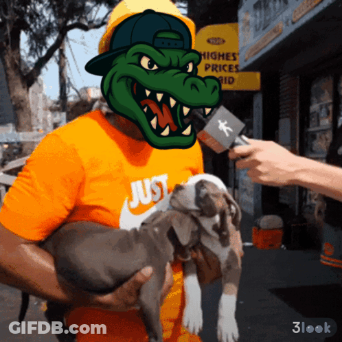 A Man Holding A Dog With A Crocodile Mask On His Head GIF