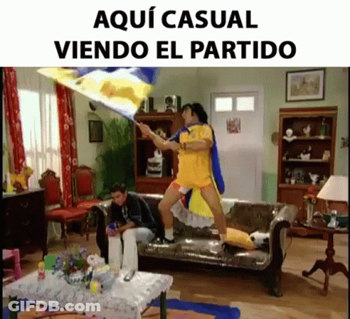 A Man Holding A Flag In A Living Room With The Words Aqui Casual Viendo El Partido On The Bottom GIF