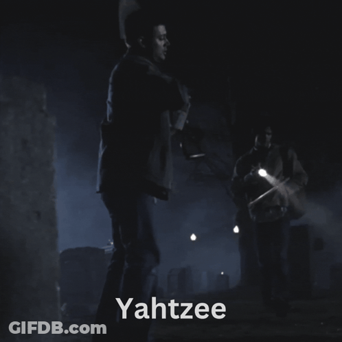 A Man Holding A Flashlight In A Dark Room With The Word Yahtzee On The Bottom GIF