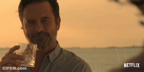 A Man Holding A Glass With A Netflix Logo In The Corner GIF