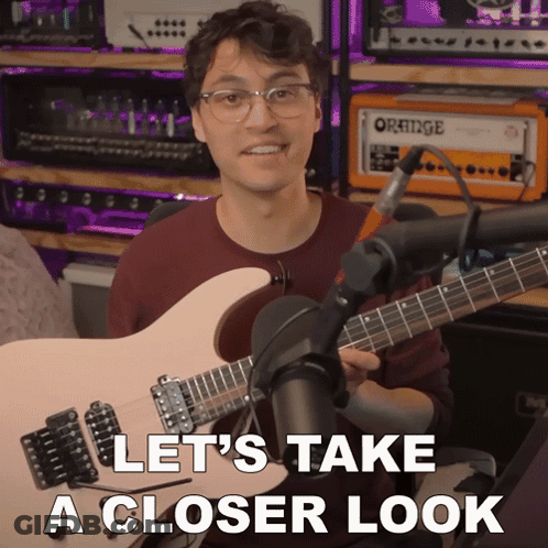 A Man Holding A Guitar In Front Of An Orange Amplifier GIF