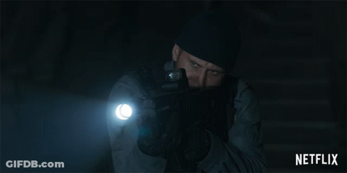 A Man Holding A Gun And A Flashlight With A Netflix Logo In The Corner GIF