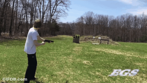 A Man Holding A Gun In A Field With Bgs Written In White GIF