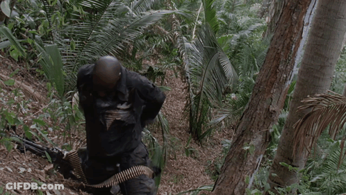 A Man Holding A Gun In A Jungle With The Words I 'M Gonna Have Me Some Fun Below Him GIF