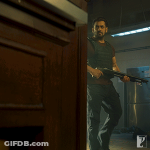 A Man Holding A Gun In A Room With A Sign That Says Exit On It GIF