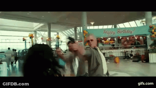 A Man Holding A Gun In Front Of A Happy Birthday Sign GIF