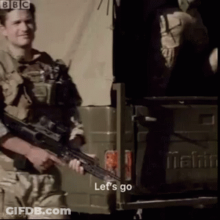 A Man Holding A Gun In Front Of A Mahindra Truck GIF