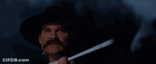 A Man Holding A Gun With The Words " Hell 'S Coming With Me " Behind Him GIF