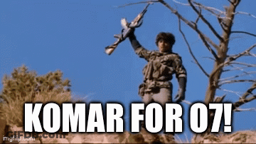 A Man Holding A Gun With The Words Komar For 07 Written Below Him GIF