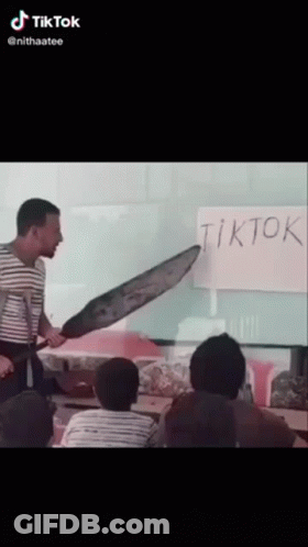 A Man Holding A Large Knife In Front Of A White Board That Says Tiktok GIF