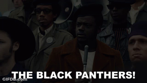 A Man Holding A Microphone In Front Of A Crowd With The Words The Black Panthers Below Him GIF