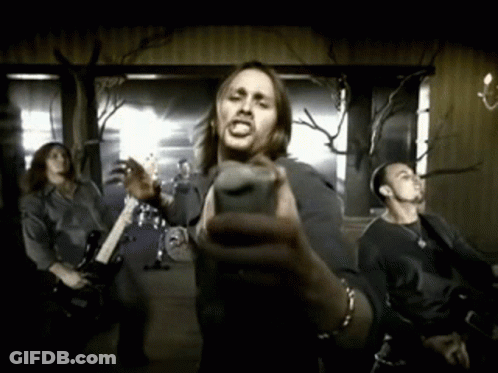 A Man Holding A Microphone In Front Of A Group Of People GIF