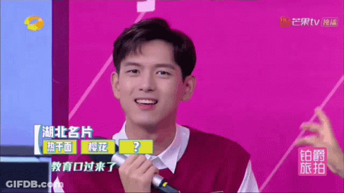 A Man Holding A Microphone In Front Of A Purple Background With Chinese Writing GIF