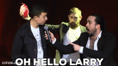 A Man Holding A Microphone Is Pointing At Another Man With The Words Oh Hello Larry Above Him GIF