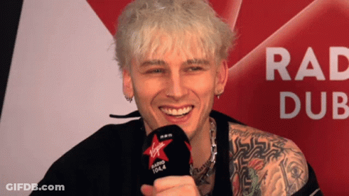A Man Holding A Microphone That Says Virgin Radio 104.4 On It GIF