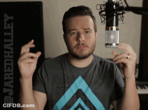 A Man Holding A Microphone With The Words @Cordhalley Behind Him GIF