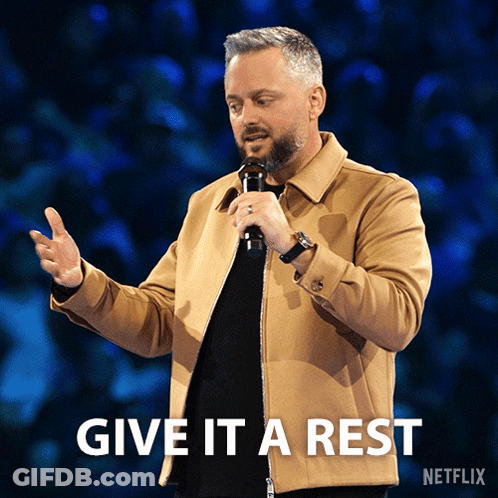 A Man Holding A Microphone With The Words Give It A Rest Written Below Him GIF