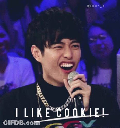 A Man Holding A Microphone With The Words " I Like Cookie " Behind Him GIF