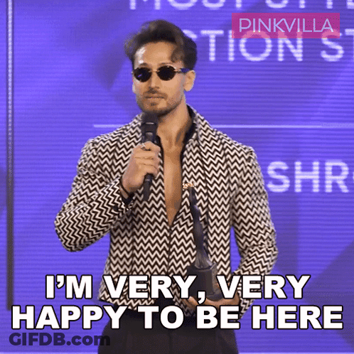 A Man Holding A Microphone With The Words I 'M Very Very Happy To Be Here GIF