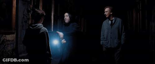 A Man Holding A Piece Of Paper Is Surrounded By Two Other Men In A Dark Room GIF