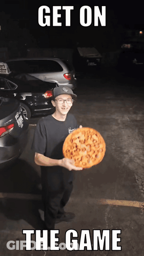 A Man Holding A Pizza With The Words Get On The Game Written Below Him GIF