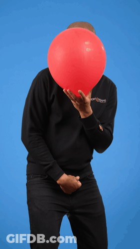A Man Holding A Red Balloon In Front Of His Face Wearing A Black Sweatshirt With The Word Jesus On The Sleeve GIF