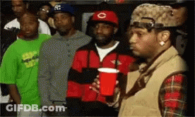 A Man Holding A Red Cup Stands In Front Of A Crowd Of People GIF