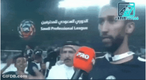 A Man Holding A Red Pro Microphone In Front Of A Saudi Professional League Logo GIF