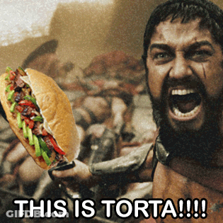 A Man Holding A Sandwich With The Words " This Is Torta !!! " On The Bottom GIF