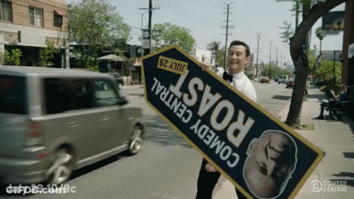 A Man Holding A Sign That Says " Comedy Central " GIF