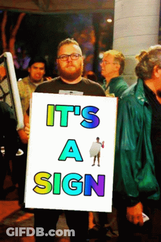 A Man Holding A Sign That Says " It 'S A Sign " GIF