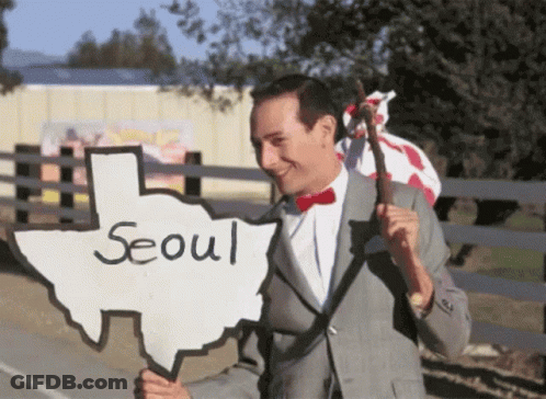 A Man Holding A Sign That Says Seoul GIF