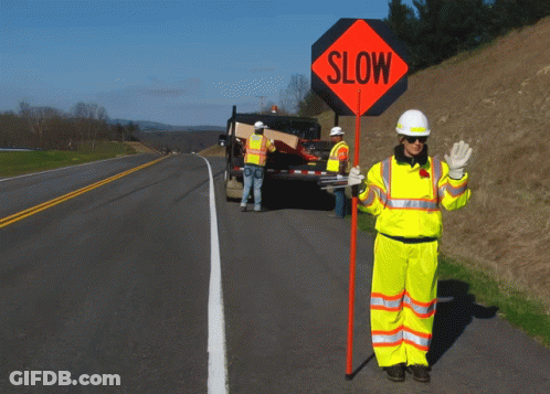 A Man Holding A Sign That Says Slow GIF