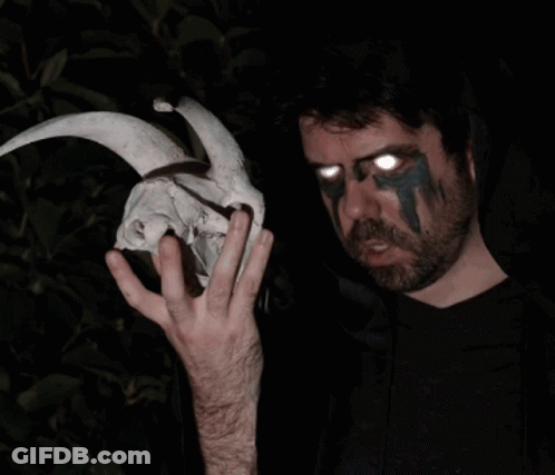 A Man Holding A Skull With Horns And Glowing Eyes GIF