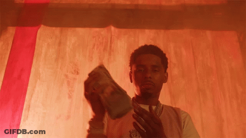 A Man Holding A Stack Of Money In Front Of A Red Background GIF