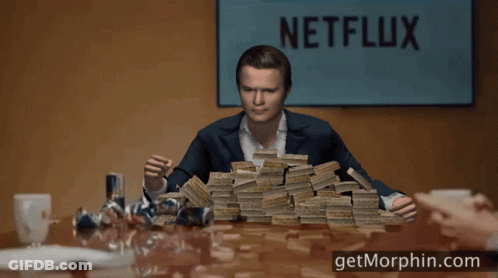 A Man Holding A Stack Of Money In Front Of A Sign That Says " Netflix " GIF