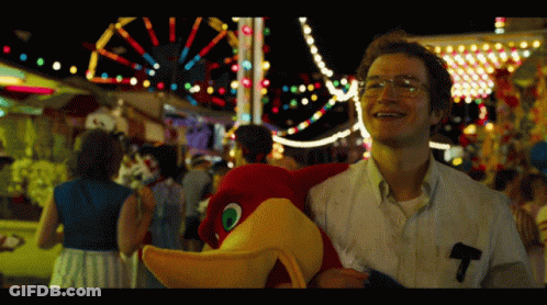 A Man Holding A Stuffed Animal With The Letter T On His Pocket GIF
