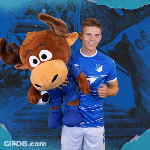 A Man Holding A Stuffed Moose Wearing A Blue Shirt That Says Tsg GIF