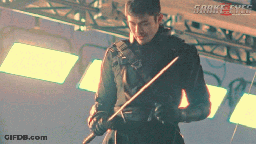A Man Holding A Sword In Front Of A Sign That Says Snakeeyes GIF