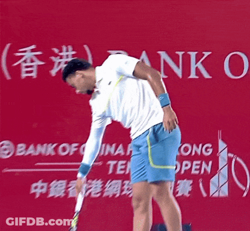 A Man Holding A Tennis Racket In Front Of A Bank Of China Sign GIF