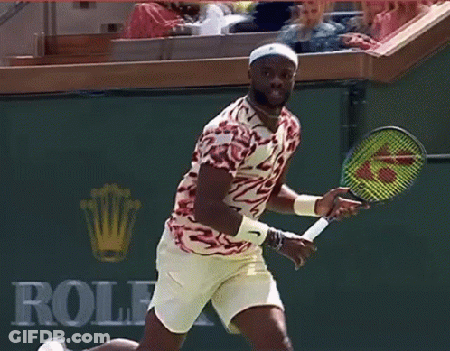 A Man Holding A Tennis Racket In Front Of A Bnp Sign GIF