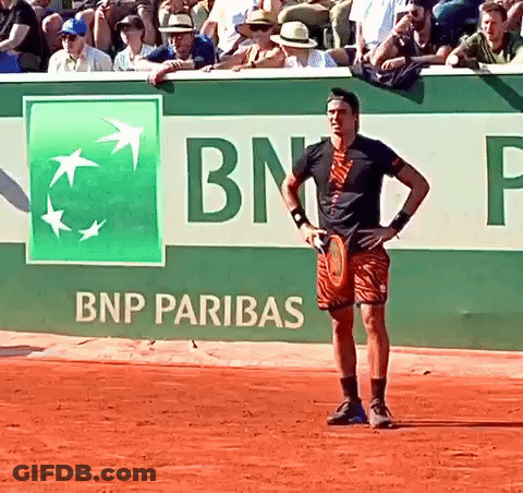A Man Holding A Tennis Racquet In Front Of A Bnp Pariba Sign GIF