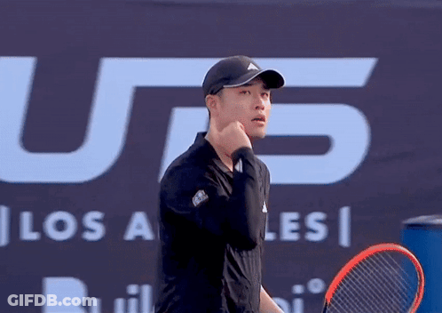 A Man Holding A Tennis Racquet In Front Of A Sign That Says U.s. GIF