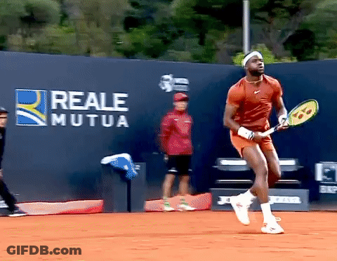 A Man Holding A Tennis Racquet In Front Of A Wall That Has Reale Mutua Written On It GIF