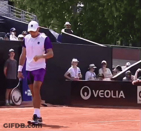 A Man Holding A Tennis Racquet On A Court In Front Of A Sign That Says Veolia GIF