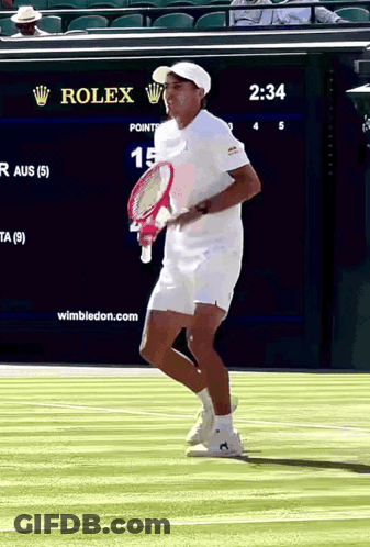 A Man Holding A Tennis Racquet On A Court With A Rolex Sign In The Background GIF